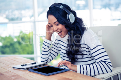 Smiling Asian woman with headphones using tablet