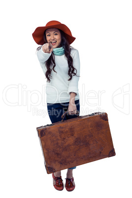 Smiling Asian woman holding luggage pointing the camera