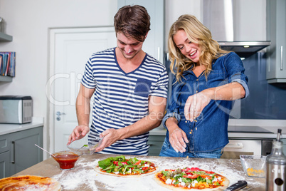 Smiling couple preparing pizza