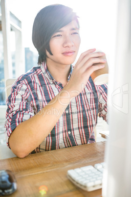 Hipster businessman drinking coffee while using computer