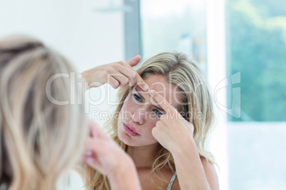 Focused beautiful young woman looking at herself in the bathroom