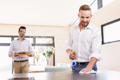 Smiling gay couple cleaning living room