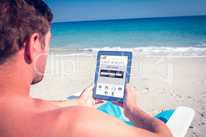 Composite image of man using digital tablet on deck chair at the