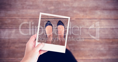 Composite image of hand holding polaroid picture