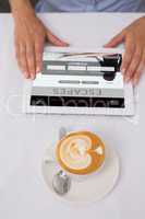 Composite image of close-up of digital tablet and coffee on tabl