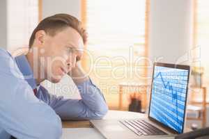 Composite image of focused businessman looking at laptop