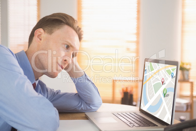 Composite image of focused businessman looking at laptop