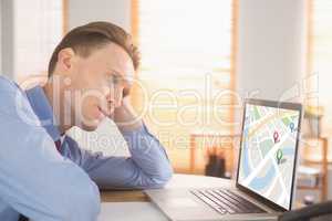 Composite image of focused businessman looking at laptop