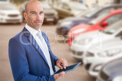 Composite image of businessman using a tablet and smiling at the