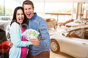 Composite image of excited couple holding money