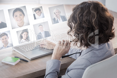 Composite image of businesswoman using laptop at desk in creativ