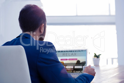Composite image of professional holding coffee cup while working