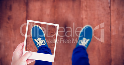 Composite image of hand holding polaroid picture