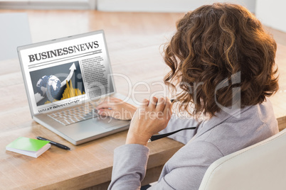 Composite image of businesswoman using laptop at desk in creativ