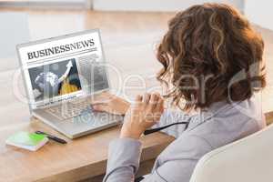 Composite image of businesswoman using laptop at desk in creativ