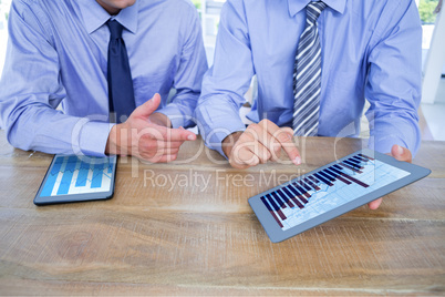 Composite image of businessmen using digital tablet at table