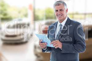 Composite image of smiling businessman using his tablet