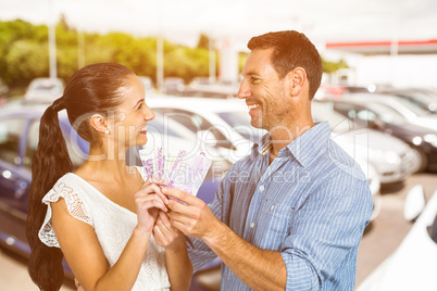 Composite image of smiling couple holding money