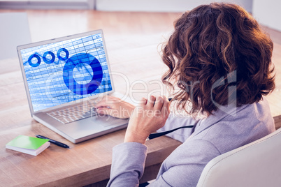 Composite image of businesswoman using laptop at desk in creativ