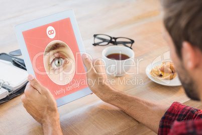 Composite image of rear view of man using tablet on wooden table