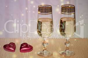 Two wine glasses filled with champagne, and candles.
