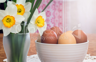 Easter eggs in a ceramic vase and flowers daffodils.
