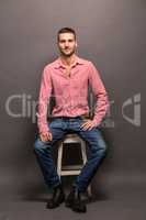 Handsome man sitting on a chair in studio