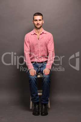 Handsome man sitting on a chair in studio