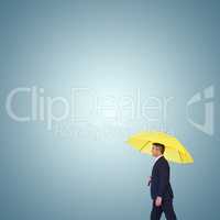 Composite image of businessman with yellow umbrella walking on w