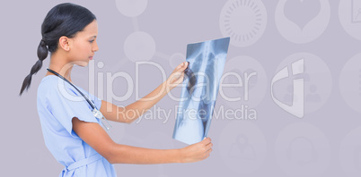 Composite image of female surgeon examining chest x-ray
