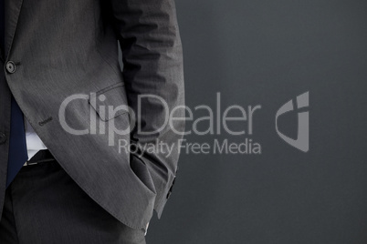 Composite image of businessman standing with hand in pocket