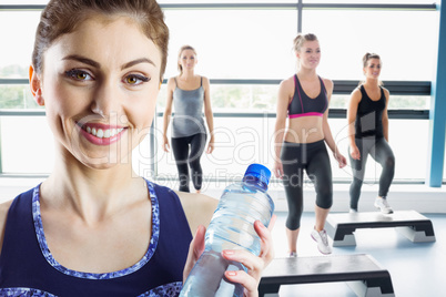 Composite image of fit brunette holding water bottle