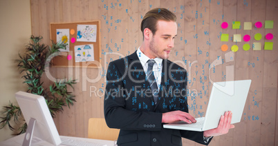 Composite image of businessman in suit typing on laptop
