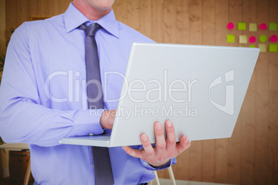 Composite image of businessman using a laptop