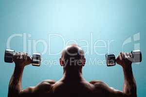 Composite image of rear view of muscular man lifting dumbbells