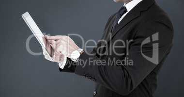 Composite image of businessman in suit using digital tablet