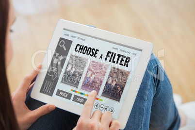 Composite image of teen using a tablet pc sitting on the floor