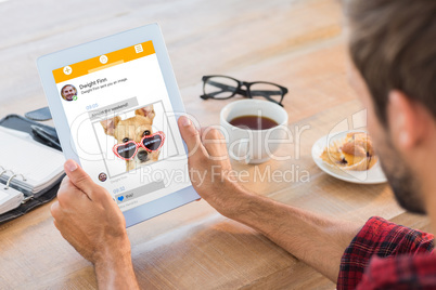 Composite image of rear view of man using tablet on wooden table