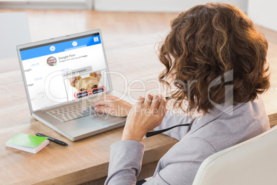 Composite image of businesswoman using laptop at desk in creativ