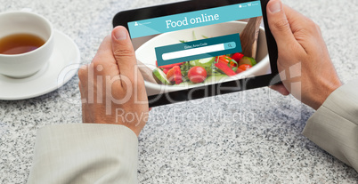 Composite image of businessman holding small tablet at table