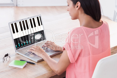 Composite image of businesswoman using laptop at desk in creativ