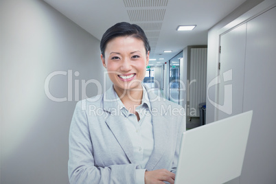 Composite image of businesswoman using laptop with colleagues be