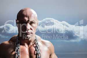 Composite image of portrait of confident muscular man with chain