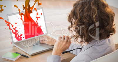 Composite image of businesswoman using laptop at desk in creativ