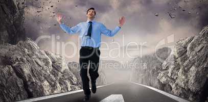 Composite image of happy businessman running with hands up