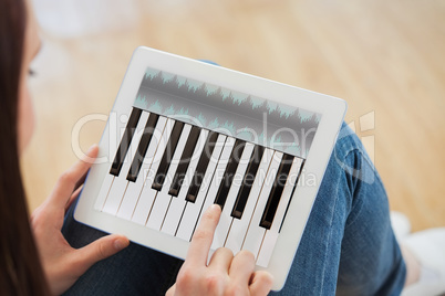 Composite image of teen using a tablet pc sitting on the floor