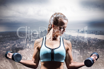 Composite image of sporty woman lifting dumbbells
