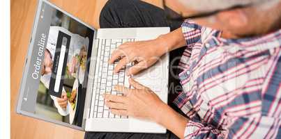 Composite image of man using laptop while sitting on floor at ho