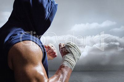 Composite image of muscular man in blue hood with fighting stanc