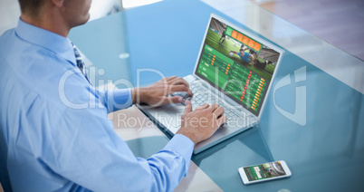 Composite image of businessman using his laptop